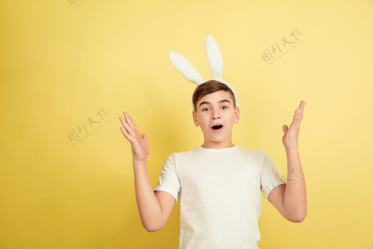 耳朵惊讶 震惊白人男孩作为一个复活节兔子在黄色的工作室背景复活节快乐的问候漫画肖像有趣