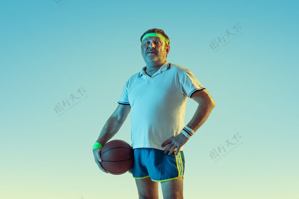 动作高级男子在霓虹灯下的梯度背景下打篮球身材魁梧的白种人男模保持活跃 运动精神教练欢呼男性