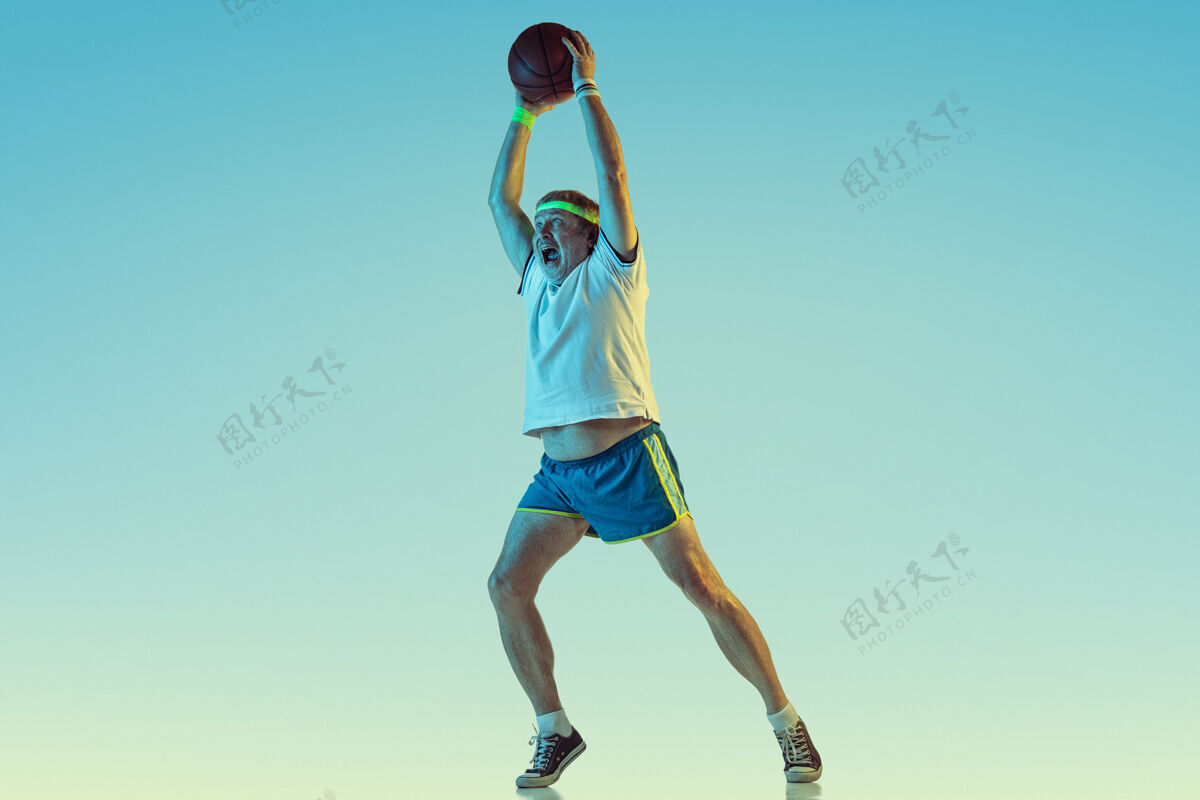 爱好高级男子在霓虹灯下的梯度背景下打篮球身材魁梧的白种人男模保持活跃 运动精神文案空间霓虹灯单身