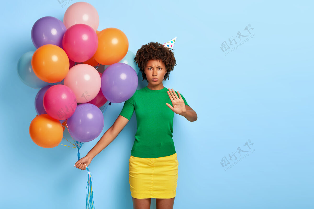 手掌不高兴的女人拿着五颜六色的气球摆着生日帽室内女人人