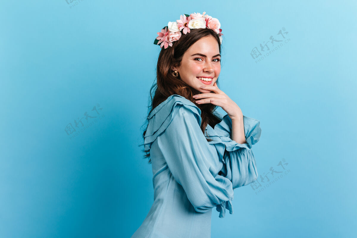 魅力迷人的女孩调皮的微笑看着相机照片中的女士穿着蓝色的衣服 戴着花冠人花冠欢呼