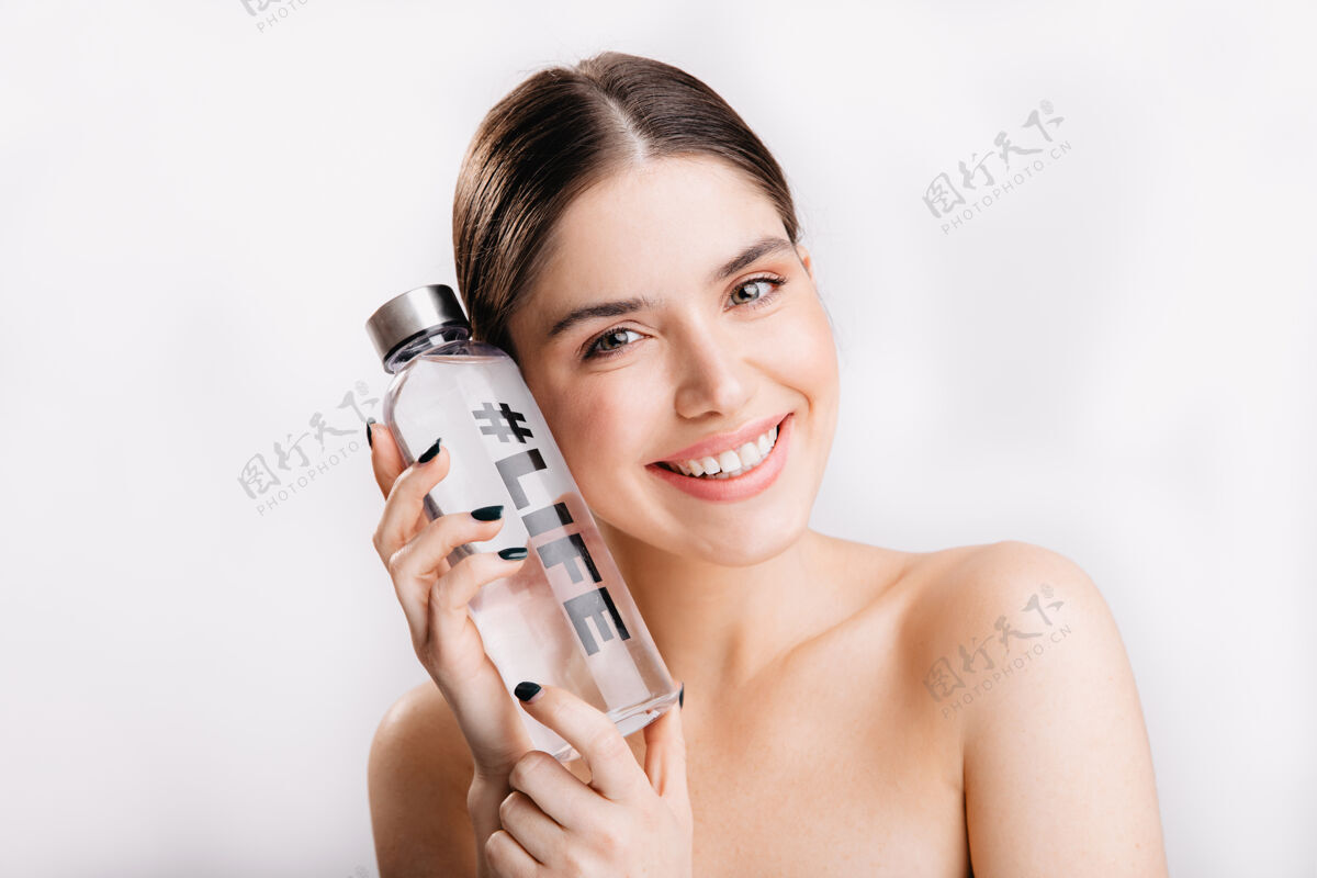 护理隔离墙上黑发女人的画像 没有化妆 心情很好积极的女人 健康的皮肤 摆着一瓶标签生活的水画像水瓶平静