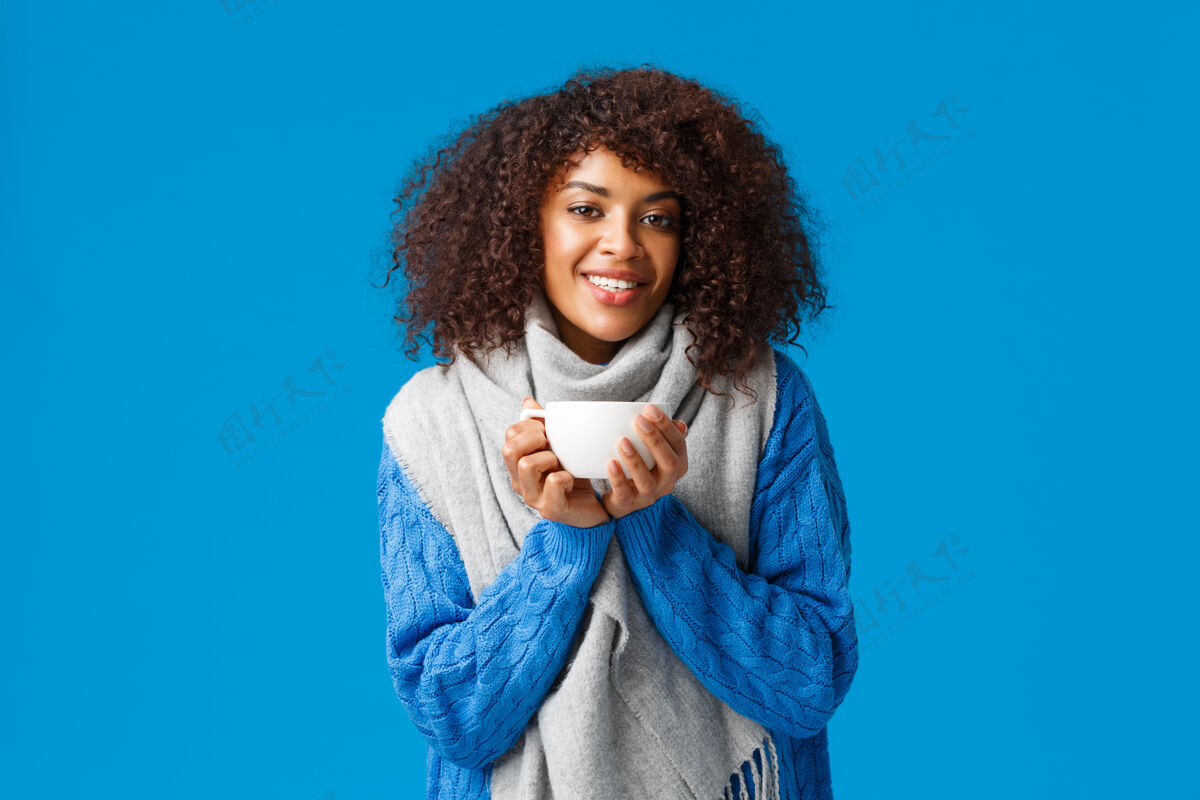 非洲舒适 温柔和温暖的概念迷人可爱的非洲裔美国妇女 留着非洲式发型 穿着毛衣和围巾 喝着热茶热身 享受着热咖啡舒适欢乐脸