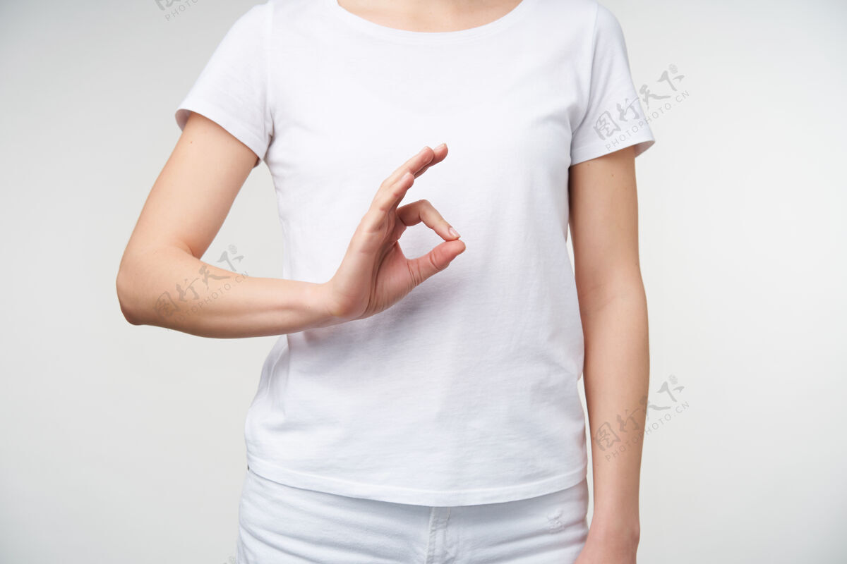 身体穿着休闲服的年轻女子站在白色背景上用手指做ok手势的室内照片手语概念手翻译符号