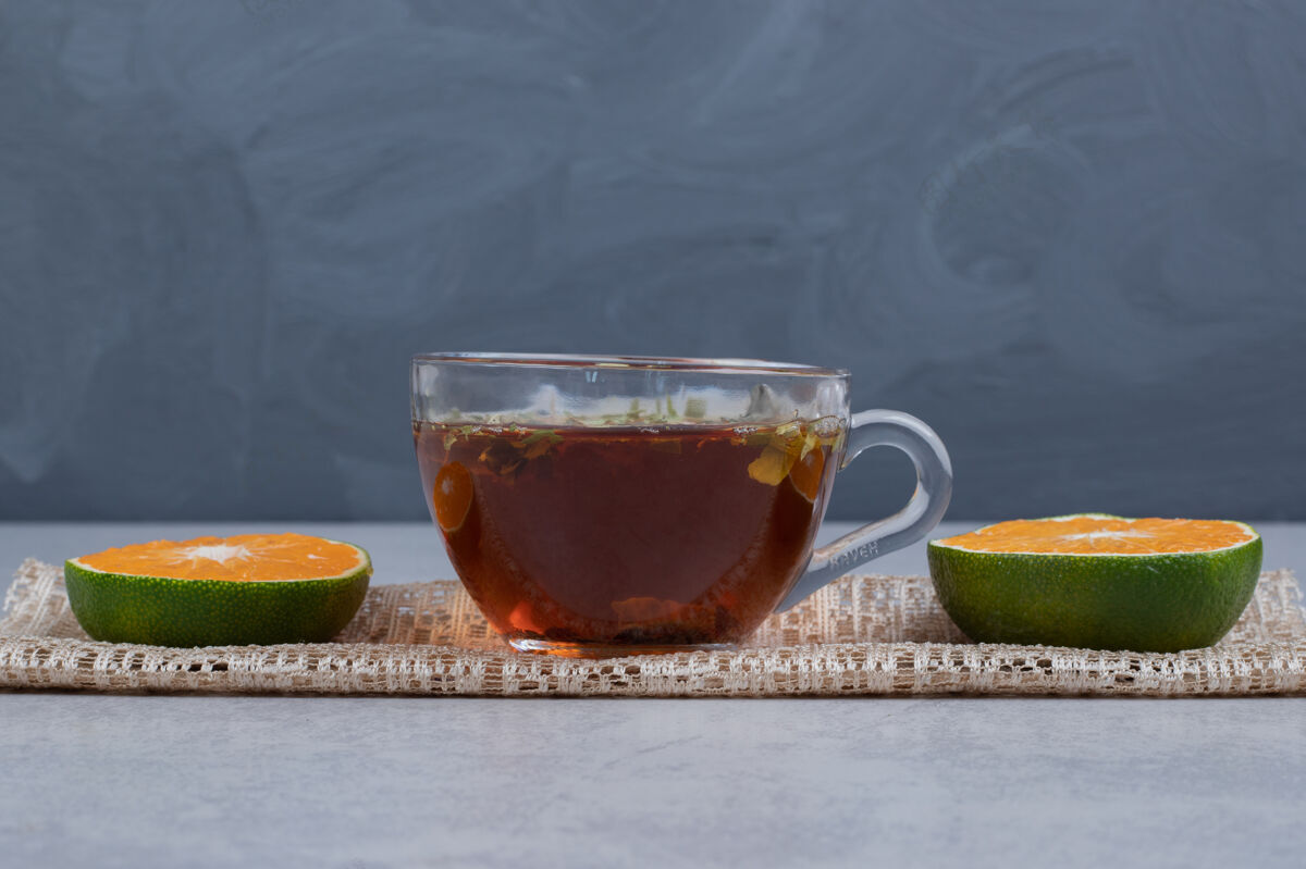 杯子在大理石桌上放几片橘子和一杯红茶高质量的照片茶饮料有机