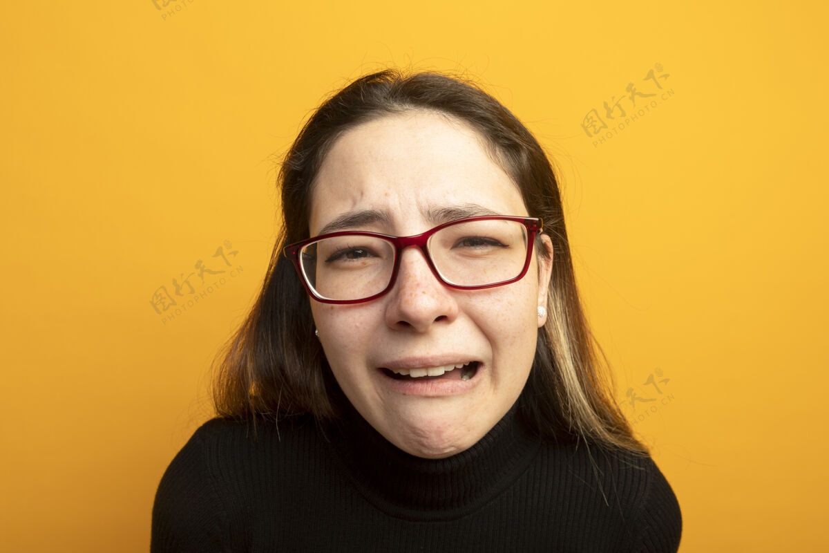 高领毛衣一个穿着黑色高领毛衣的不快乐的年轻漂亮女孩带着悲伤的表情看着镜头不开心长相橙色