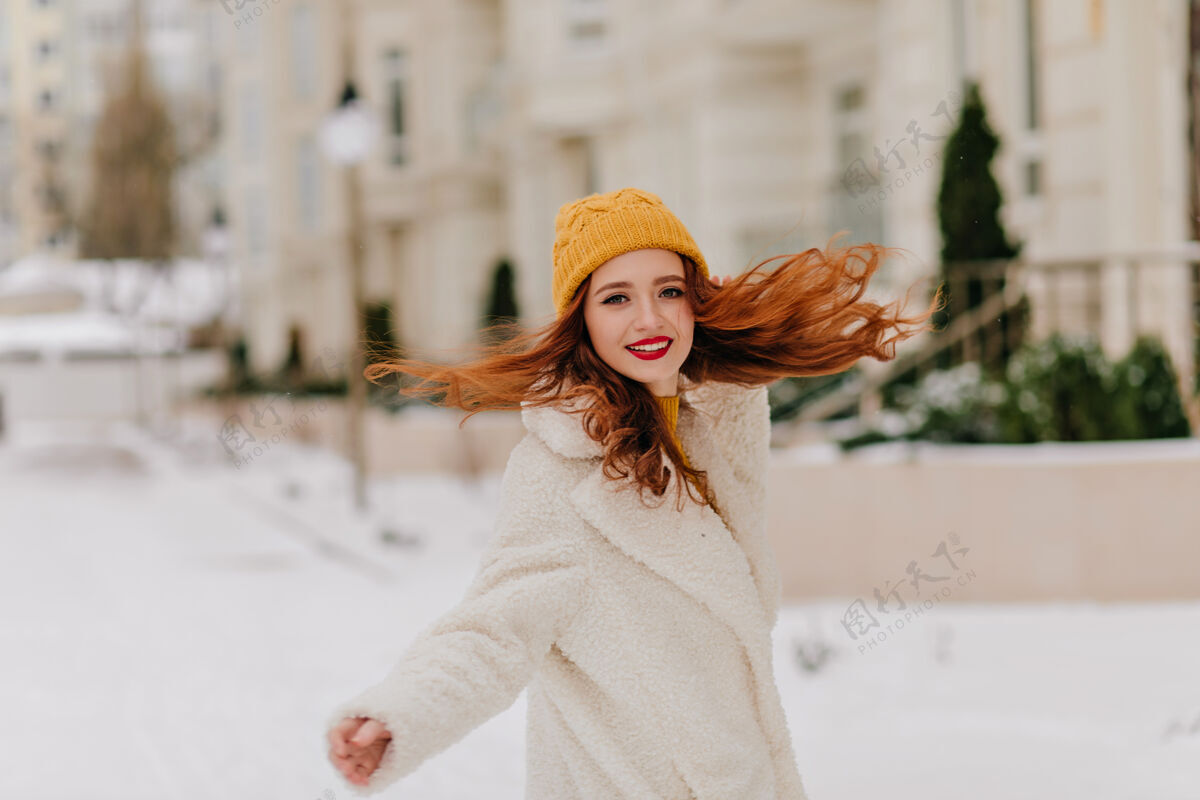 冬天可爱的女孩 长长的卷发在雪地上翩翩起舞可爱的穿着外套的女模特在冬天玩得很开心雪欧洲欢呼