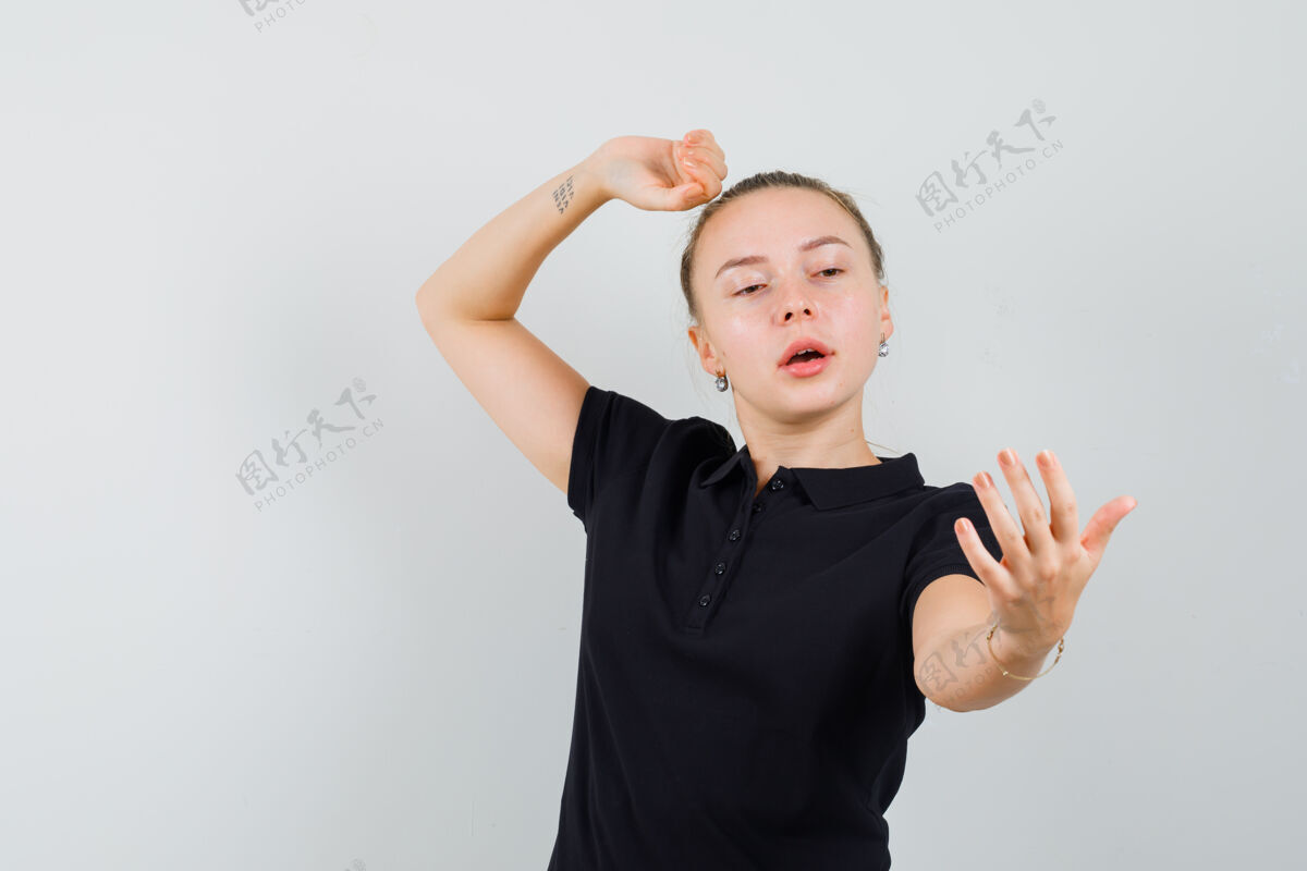 女性金发女人假装喜欢自拍 把她的手放在黑色t恤的头上模型非洲自拍