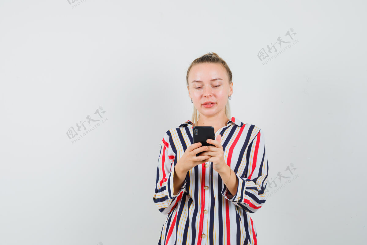 女士穿着条纹衬衫的年轻女士正在检查她的手机老年人肖像女人