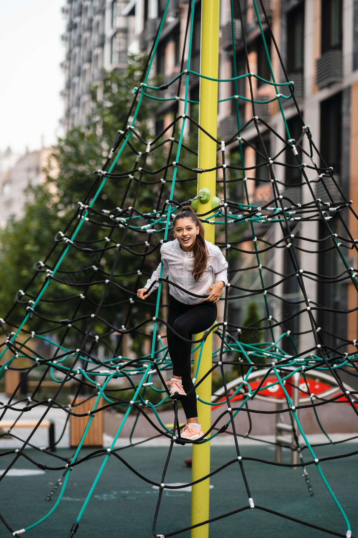活跃年轻女子在绳子金字塔上玩得很开心小攀岩游戏