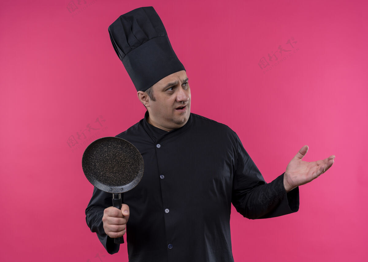 站立男厨师身穿黑色制服 头戴厨师帽站在粉色背景上男士粉色制服