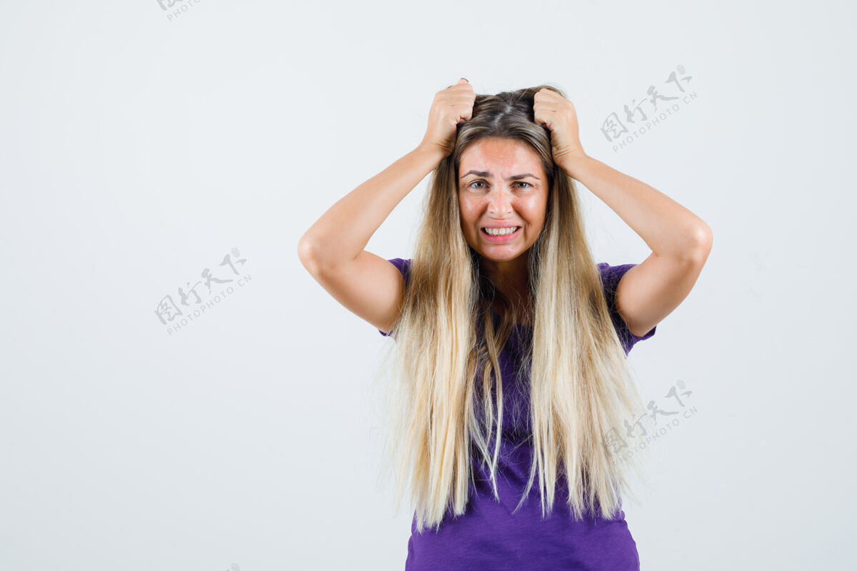 女人年轻的女士手放在头上 穿着紫罗兰色的t恤衫 看起来很渴望前视图室内兴奋人