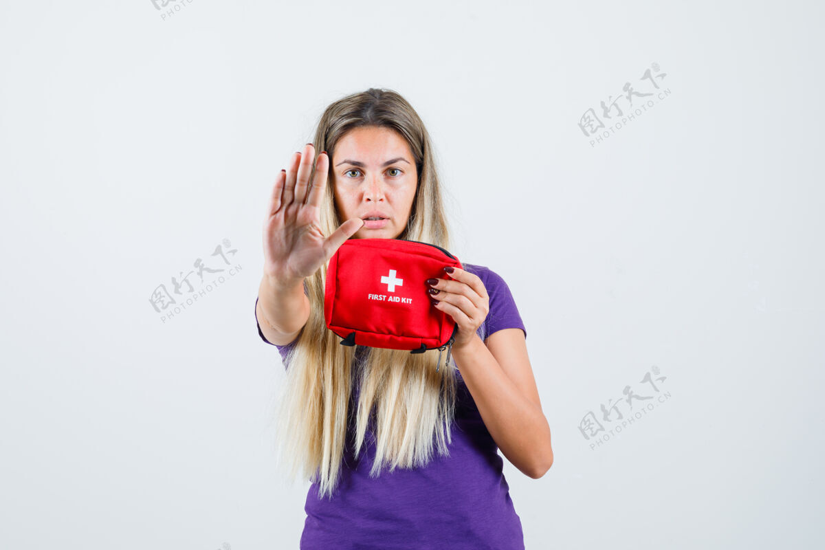 显示手持急救箱的年轻女士 身穿紫罗兰色t恤展示停车姿势 正面视图成人兴奋女士