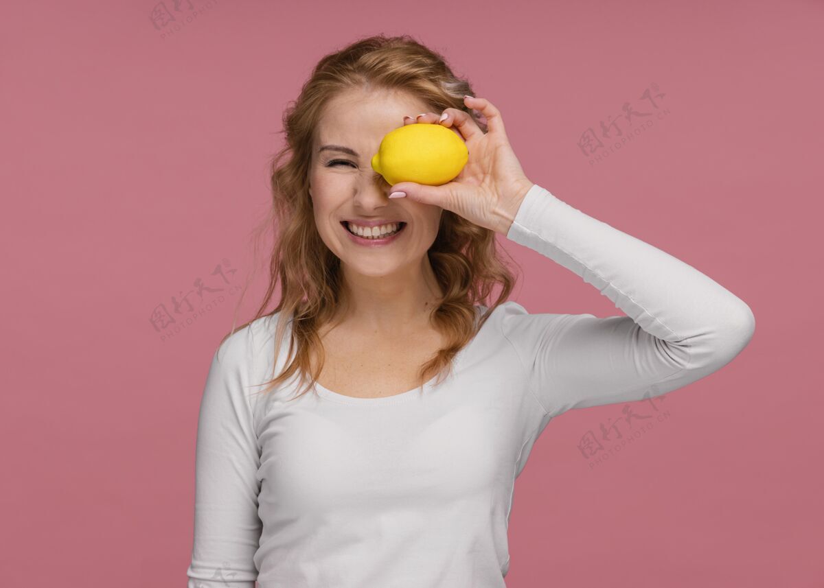 柠檬一个拿着柠檬和柠檬的顽皮女人的画像？笑年轻快乐模特