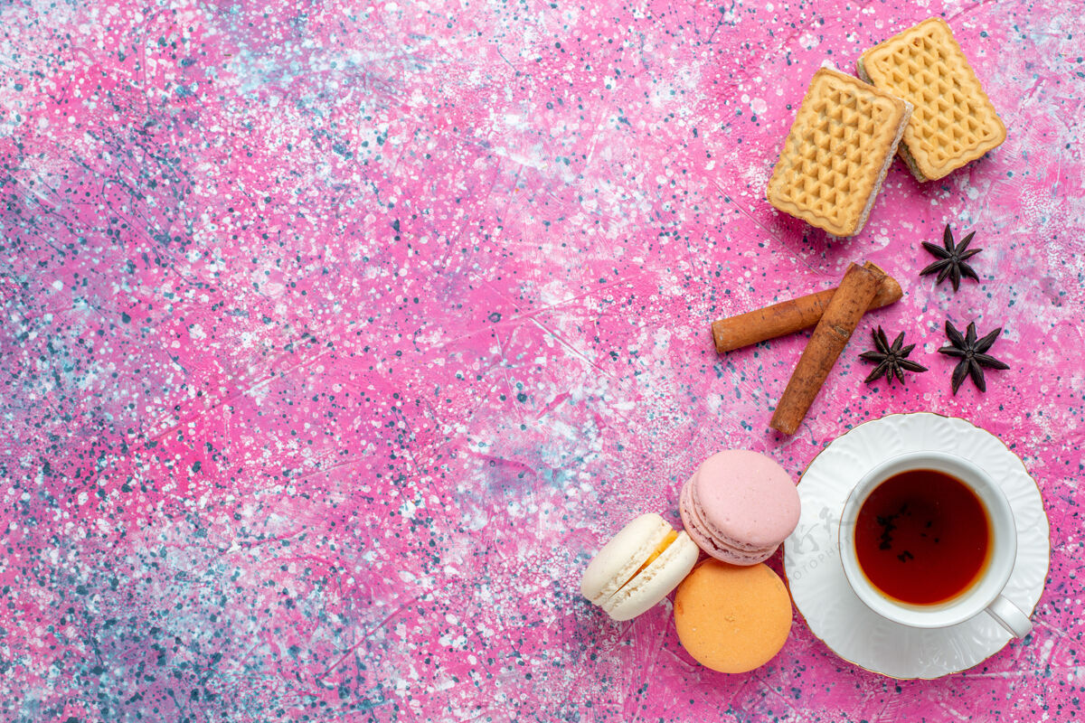 瓶子在浅粉色的桌子上 可以俯瞰一杯茶 里面放着法国马卡龙和饼干顶部饼干马卡龙