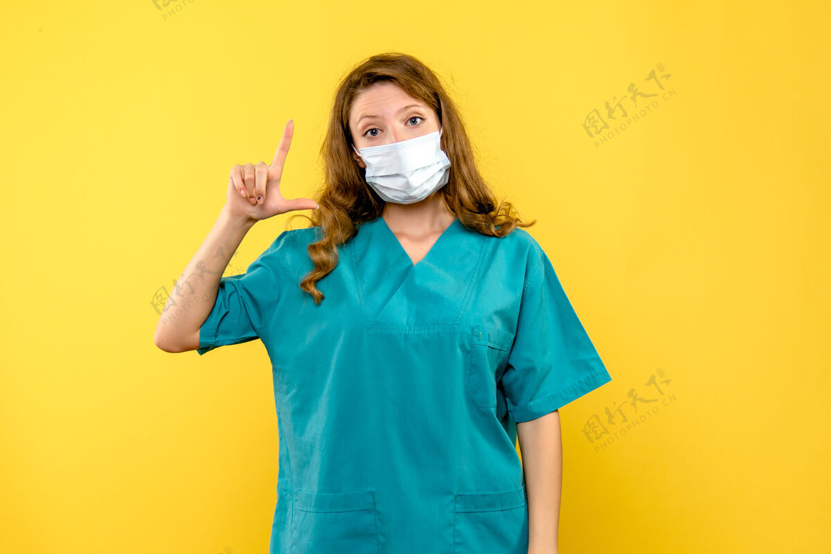 人黄色空间里戴着面具的女医生的正视图医疗面具正面