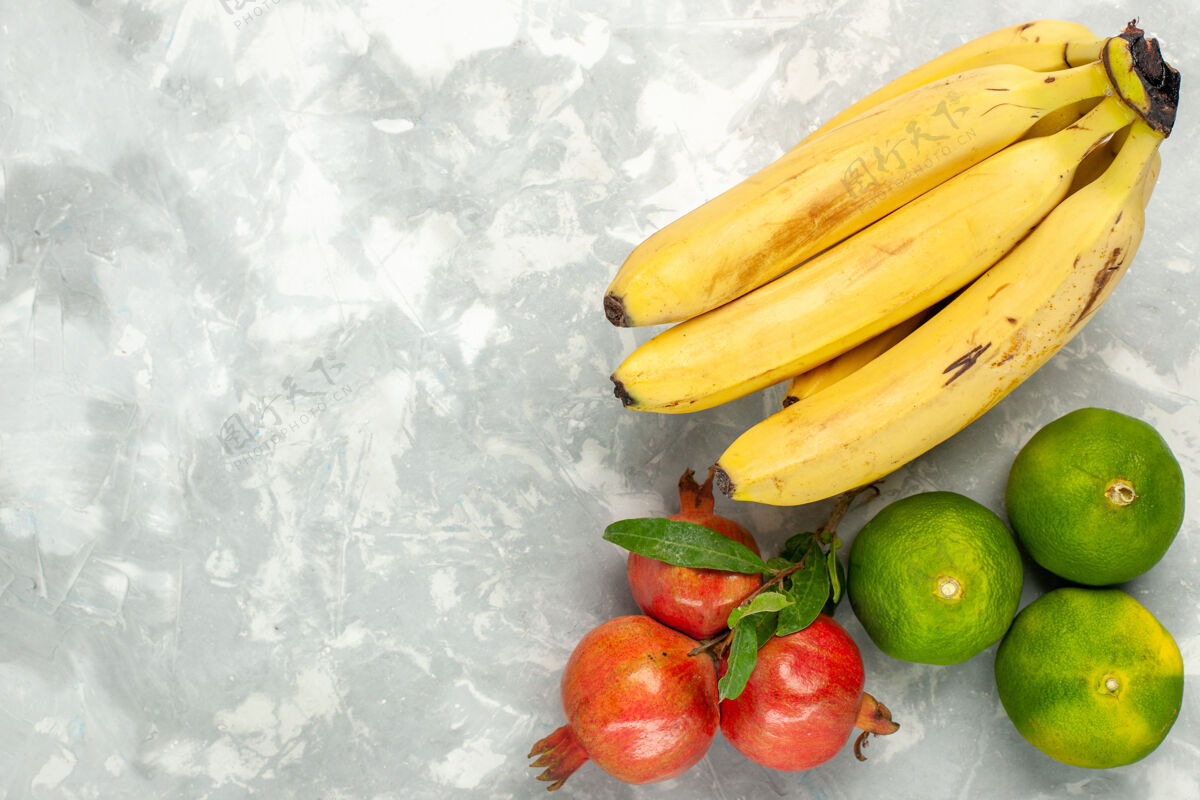 维生素在浅白色的桌子上俯瞰新鲜的黄色香蕉和石榴和橘子番茄顶级蔬菜