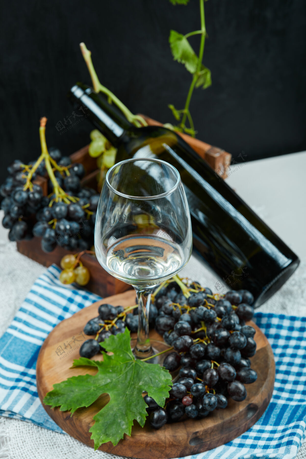 暗的一簇葡萄配一杯葡萄酒 一瓶放在白色的桌子上 蓝色的桌布食物葡萄美味