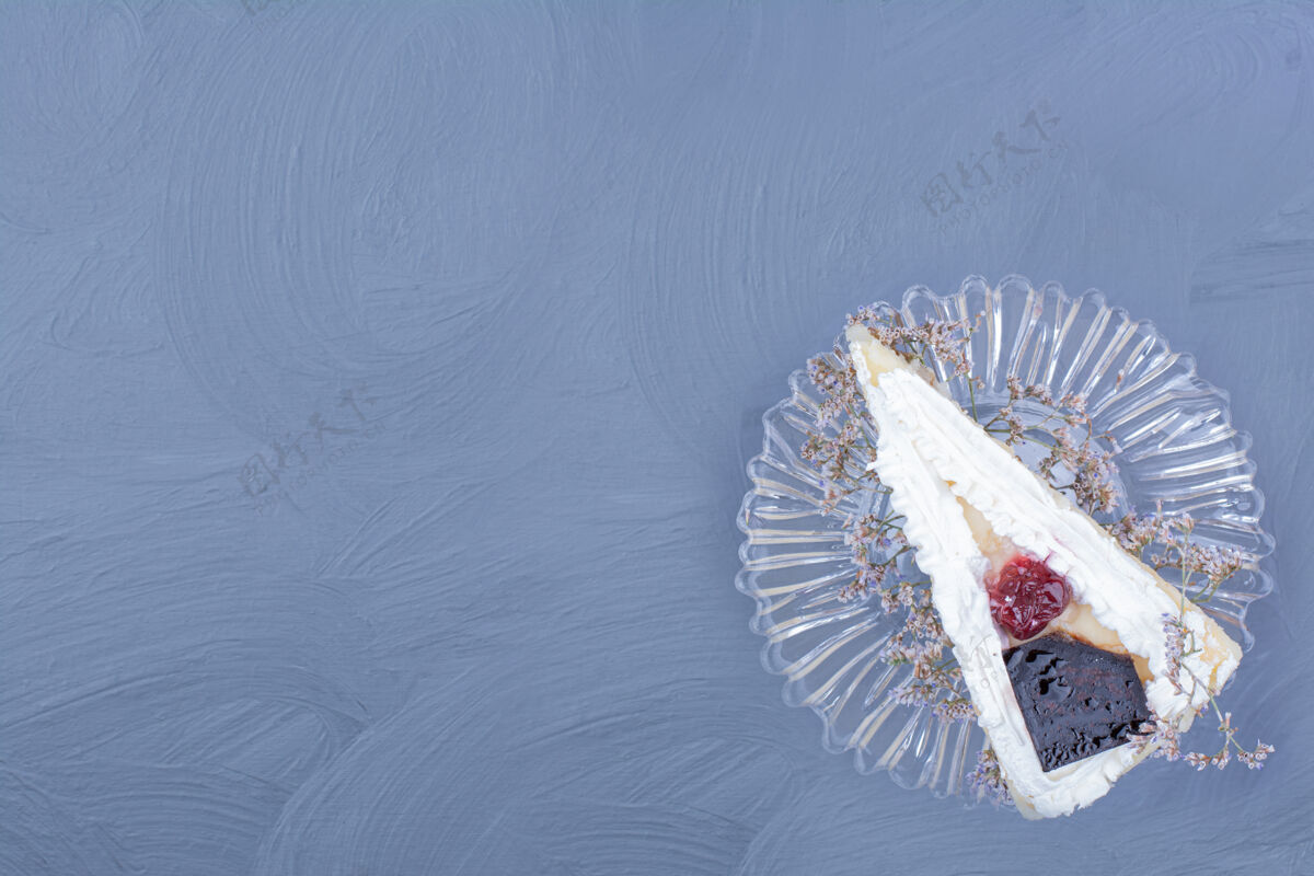 喜悦一片芝士蛋糕放在蓝色背景的玻璃碟子里餐厅艺术面粉