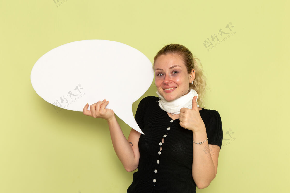 加强正面图年轻女子手捧巨大的白色招牌在绿墙上摆着病态的姿势姿势颈部支架前面