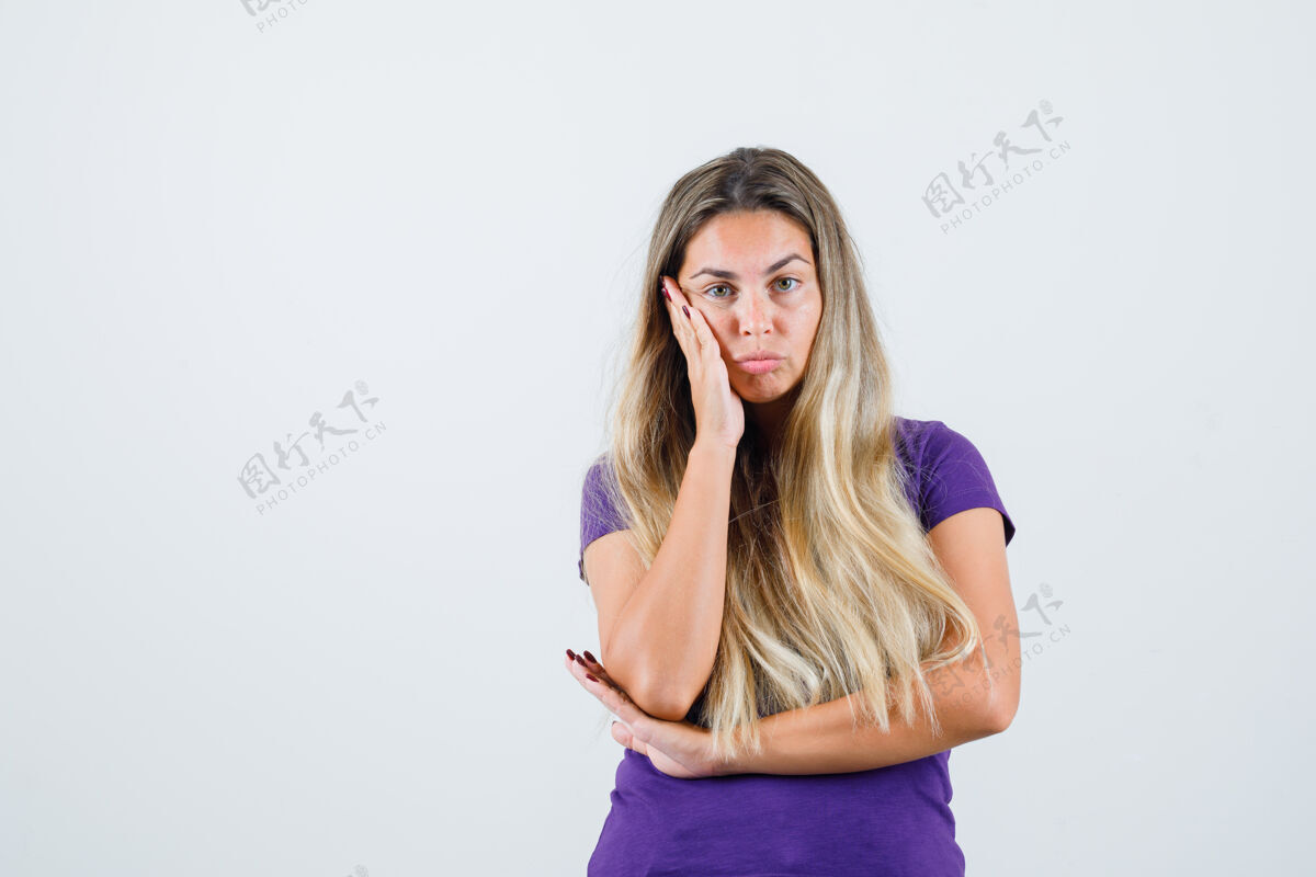 时尚一个金发女人 穿着紫罗兰色t恤 手心贴在脸颊上 面带沉思正视图持有手掌看