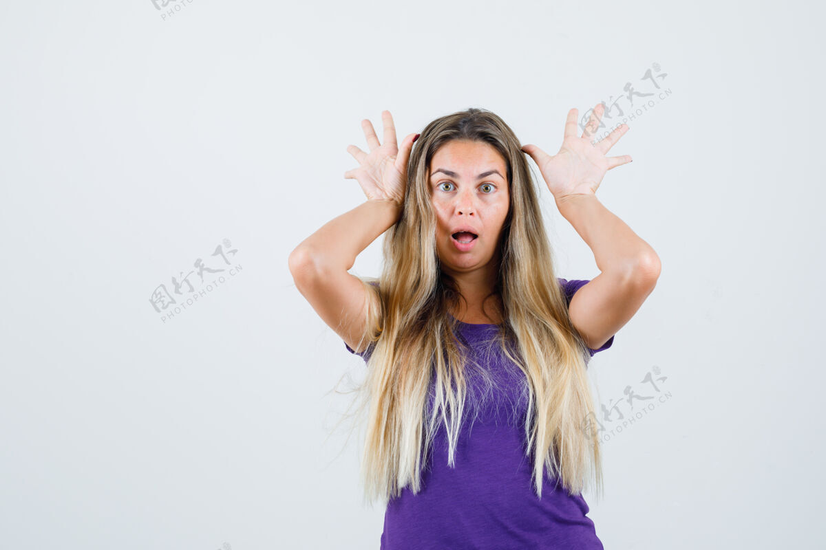时尚身着紫罗兰色t恤的金发女人做着有趣的手势 看起来很有趣 正面视图肖像手漂亮