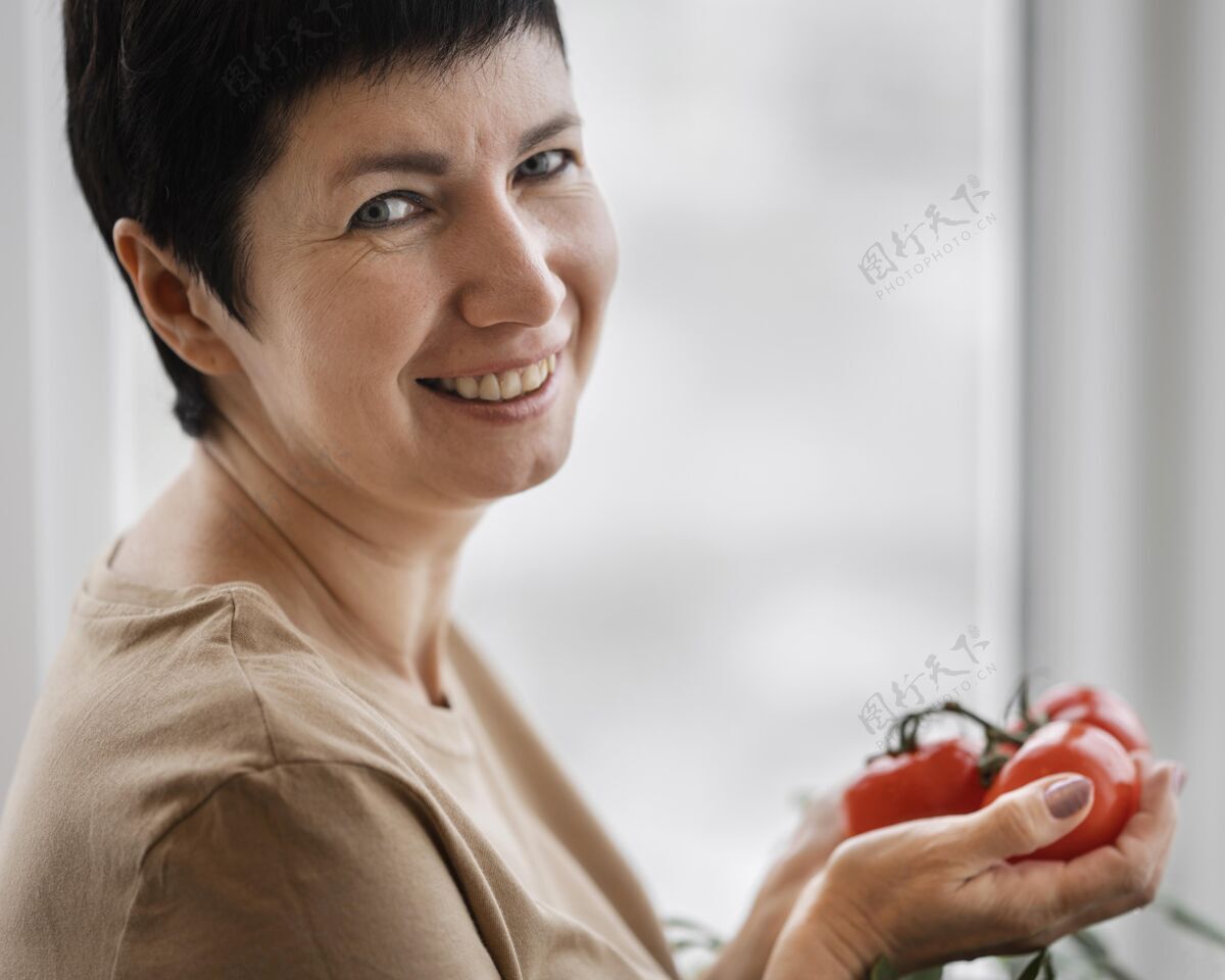 女人笑脸女人抱着自家种的西红柿的侧视图园艺草药女人