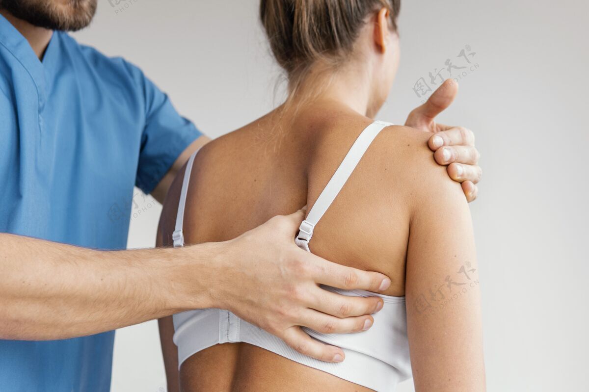 男人男性骨科治疗师正在检查女性患者的肩胛骨水平非侵入性医生
