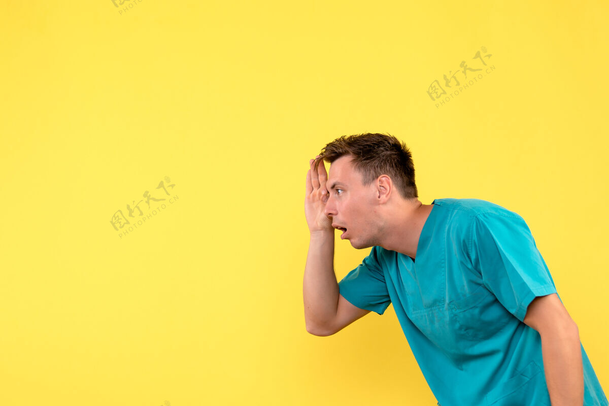 男医生前视图中的男性医生透过手指看黄色墙上商人电话成人