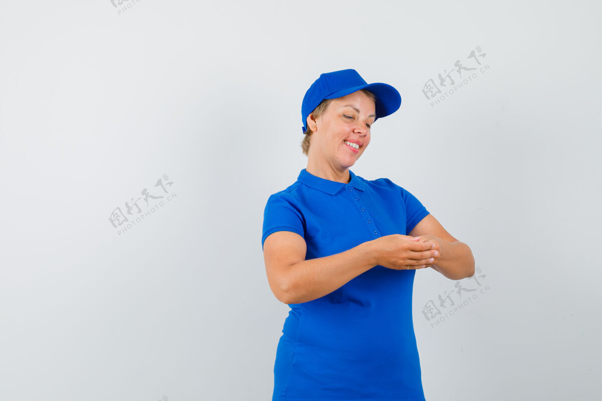 肖像成熟的女人穿着蓝色t恤看着她的手指 看起来很平静成熟脸和平