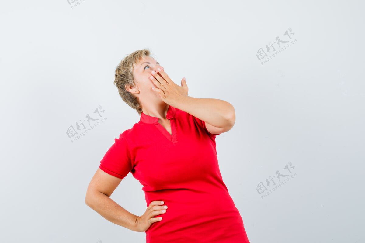 女人穿着红色t恤的成熟女人手放在嘴上 看起来很惊讶成熟红姿势