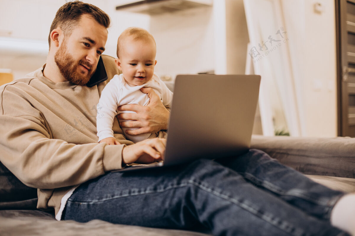 女婴年轻的父亲和他的女婴坐在一起 在家里用电脑小成人蹒跚学步