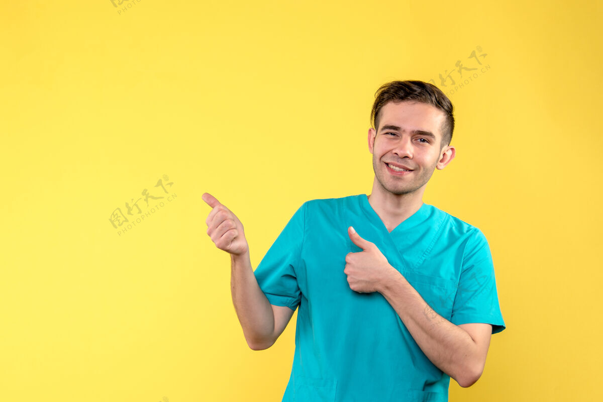 成人黄色墙上微笑的男医生的正面图男性健康医院