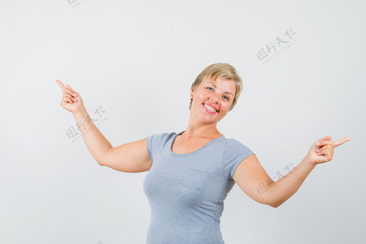 女人一个穿着灰色t恤的成熟女人指着别处 看上去很高兴灰色可爱女性