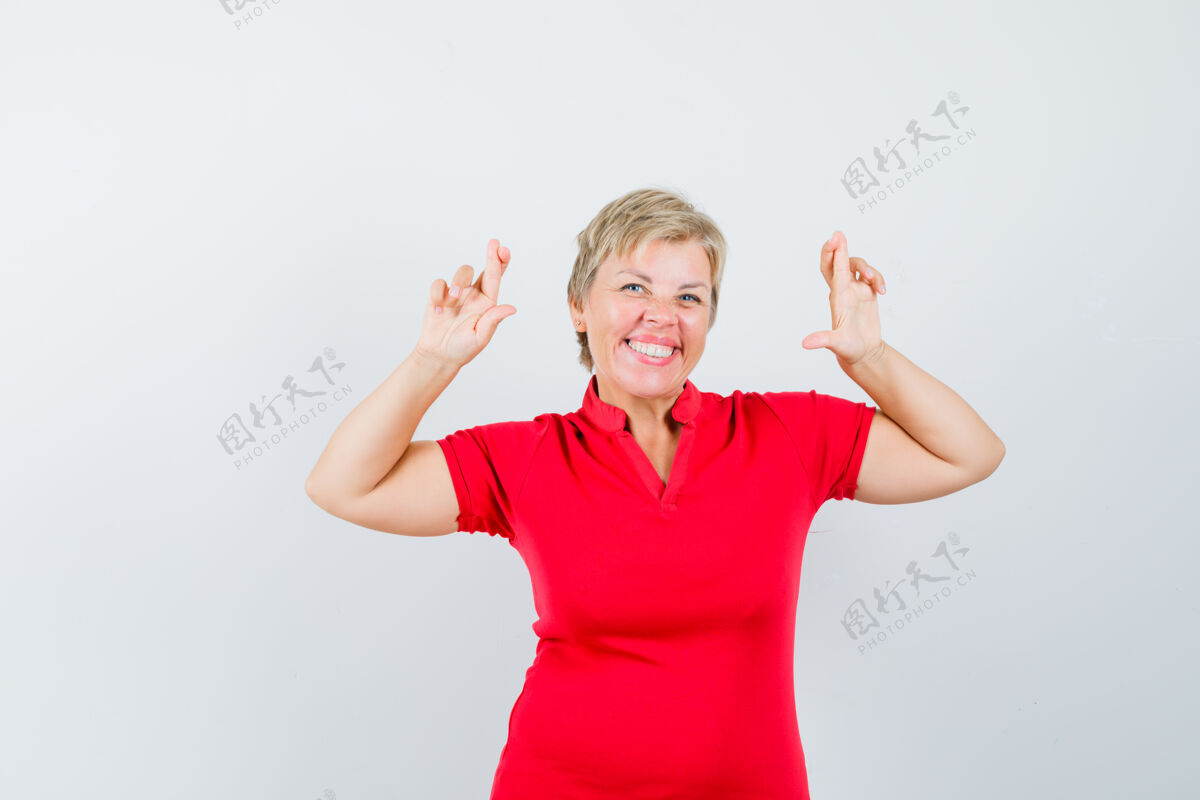 可爱成熟的女人穿着红色t恤祈祷 看起来很快乐女士欢呼姿势
