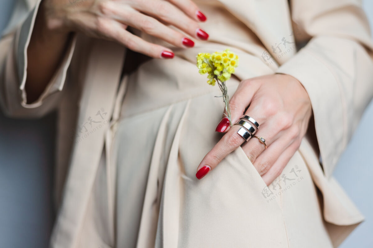 配件近距离拍摄的女人手上的红色指甲两环穿着米色西装黄色可爱的干花在口袋里植物学生长花蕾