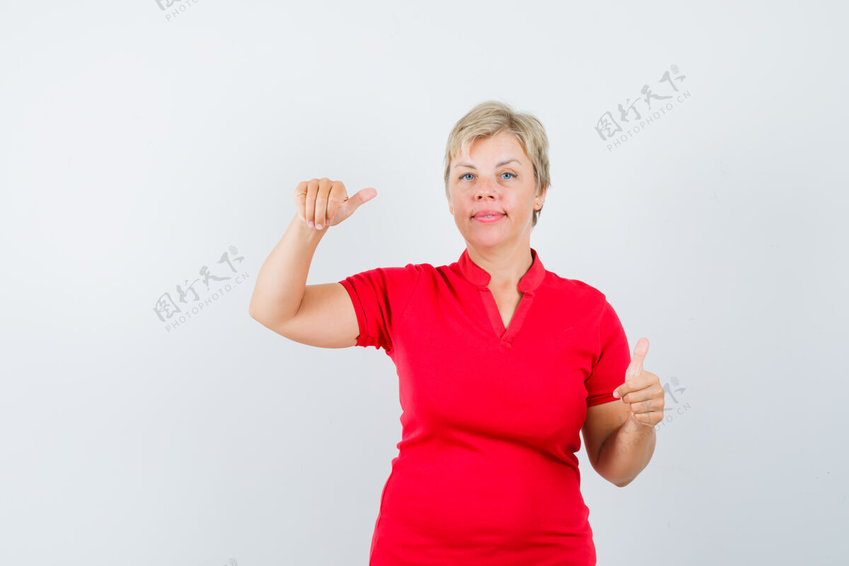 信心穿红色t恤的成熟女人假装拿着什么东西 竖起大拇指假装白发红色