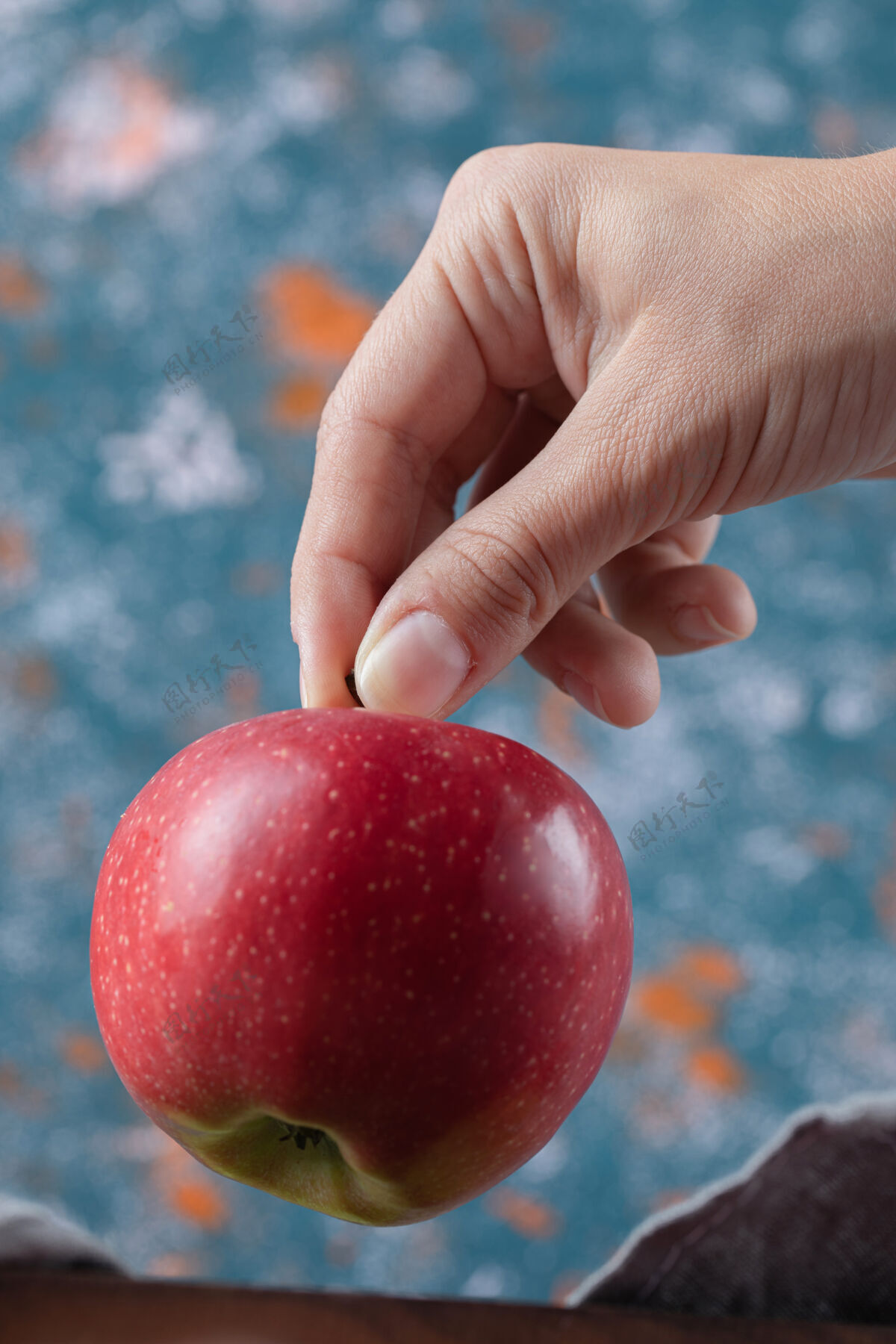新鲜手里拿着一个红苹果放在蓝色的表面上季节水果蔬菜