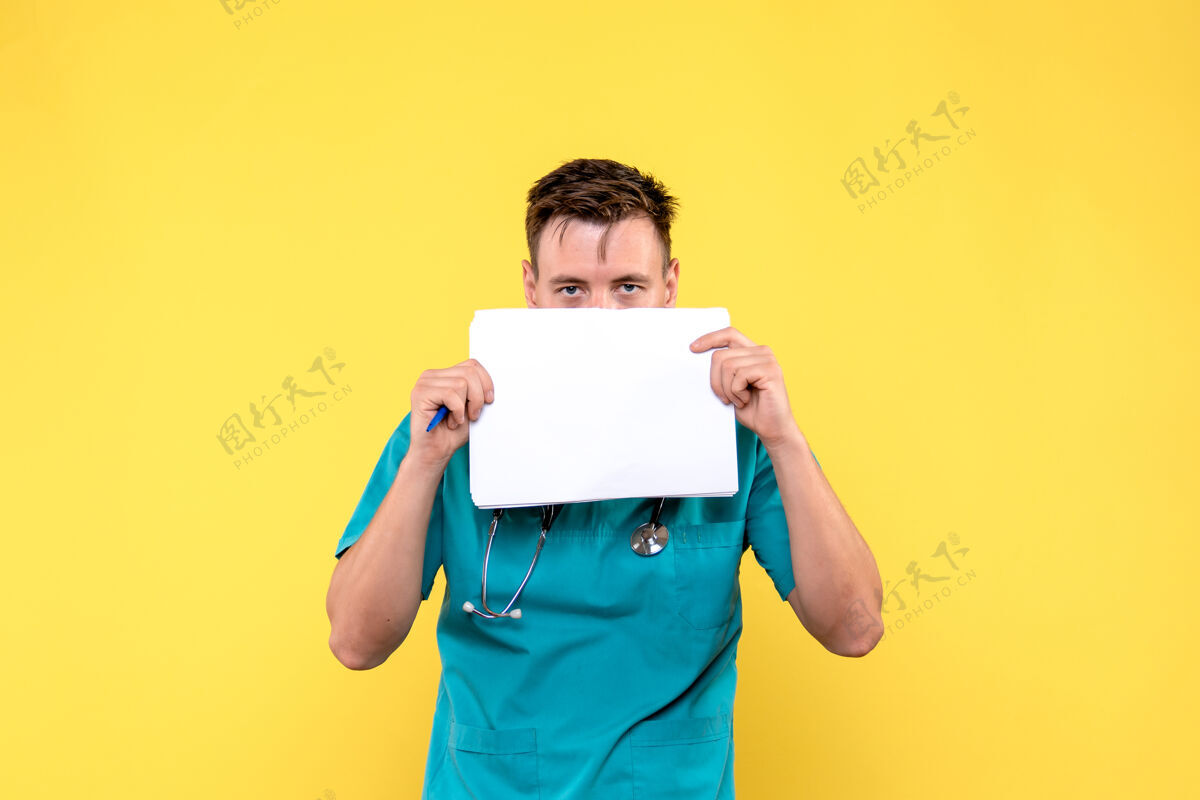 男人浅黄色墙上拿着文件的男医生的正视图前面业务快乐