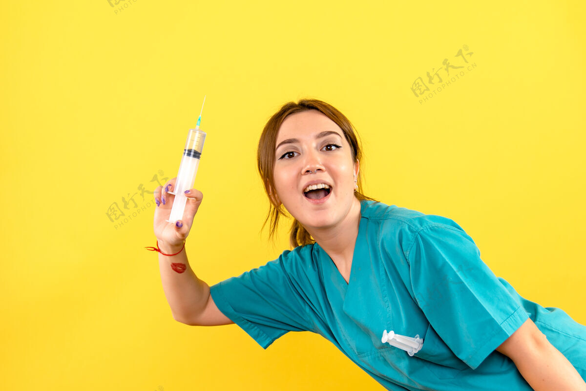 肖像黄色墙壁上的女兽医拿着巨大的注射剂的正视图宠物人专业