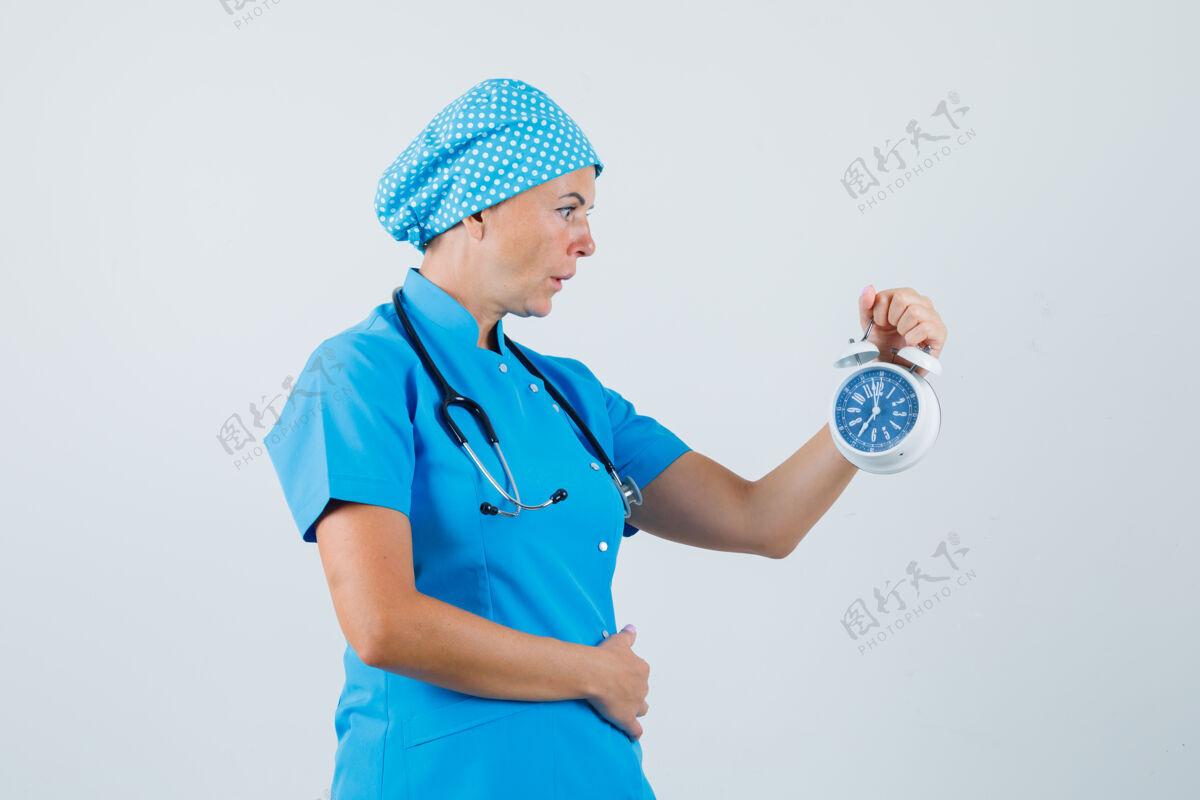 成人身着蓝色制服的女医生看着闹钟 神情激动 前视图制服疾病闹钟