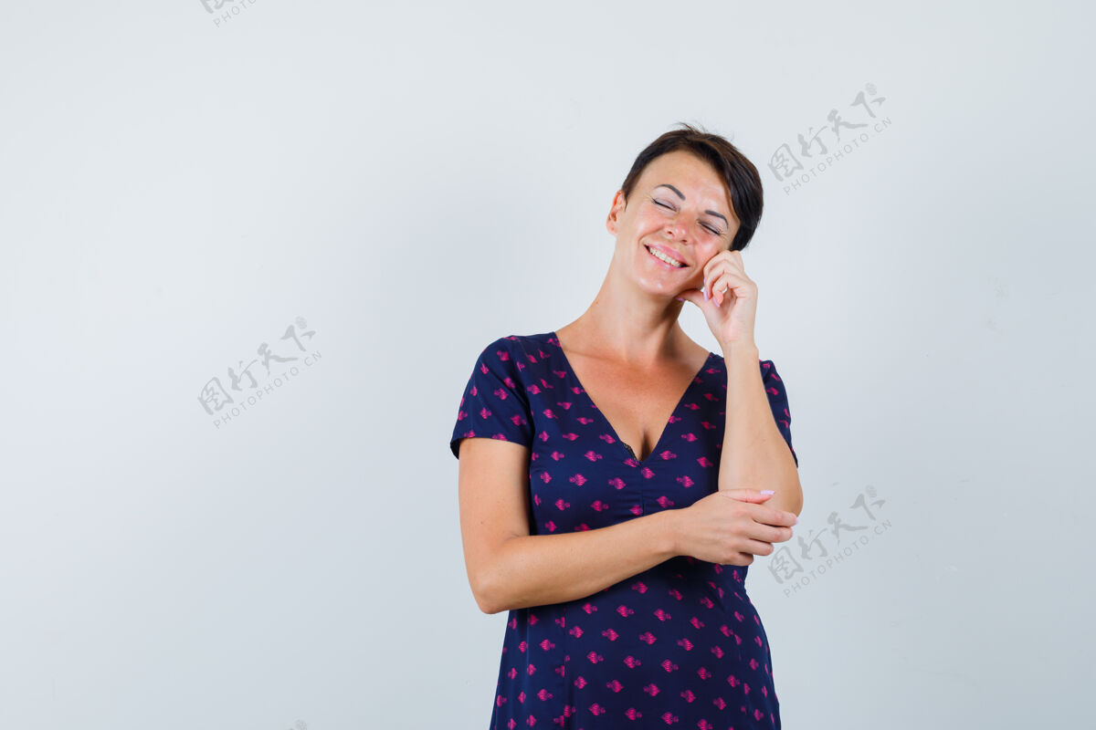 女人深色皮肤的女人 手指放在脸颊上 闭上眼睛 穿着紫色和红色图案的裙子 面带沉思 俯视前方深褐色脸颊沉思