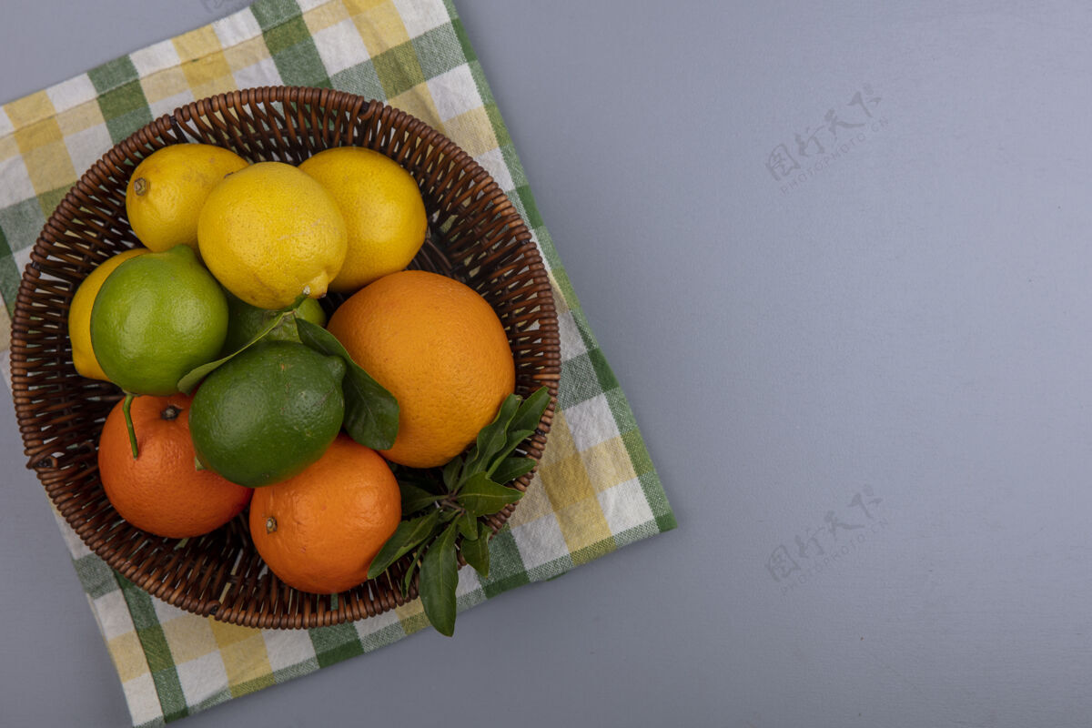 酸橙顶视图复制空间橙色柠檬和酸橙在一个篮子里黄色格子毛巾灰色背景顶部彩色黄色