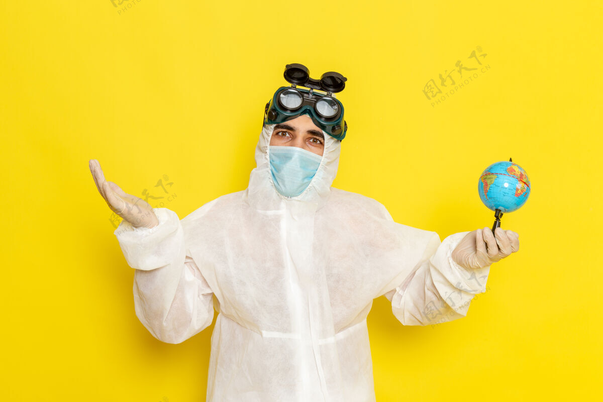 面具正面图：穿着特殊套装的男科学工作者在黄色的表面上拿着小地球仪工人服装化学