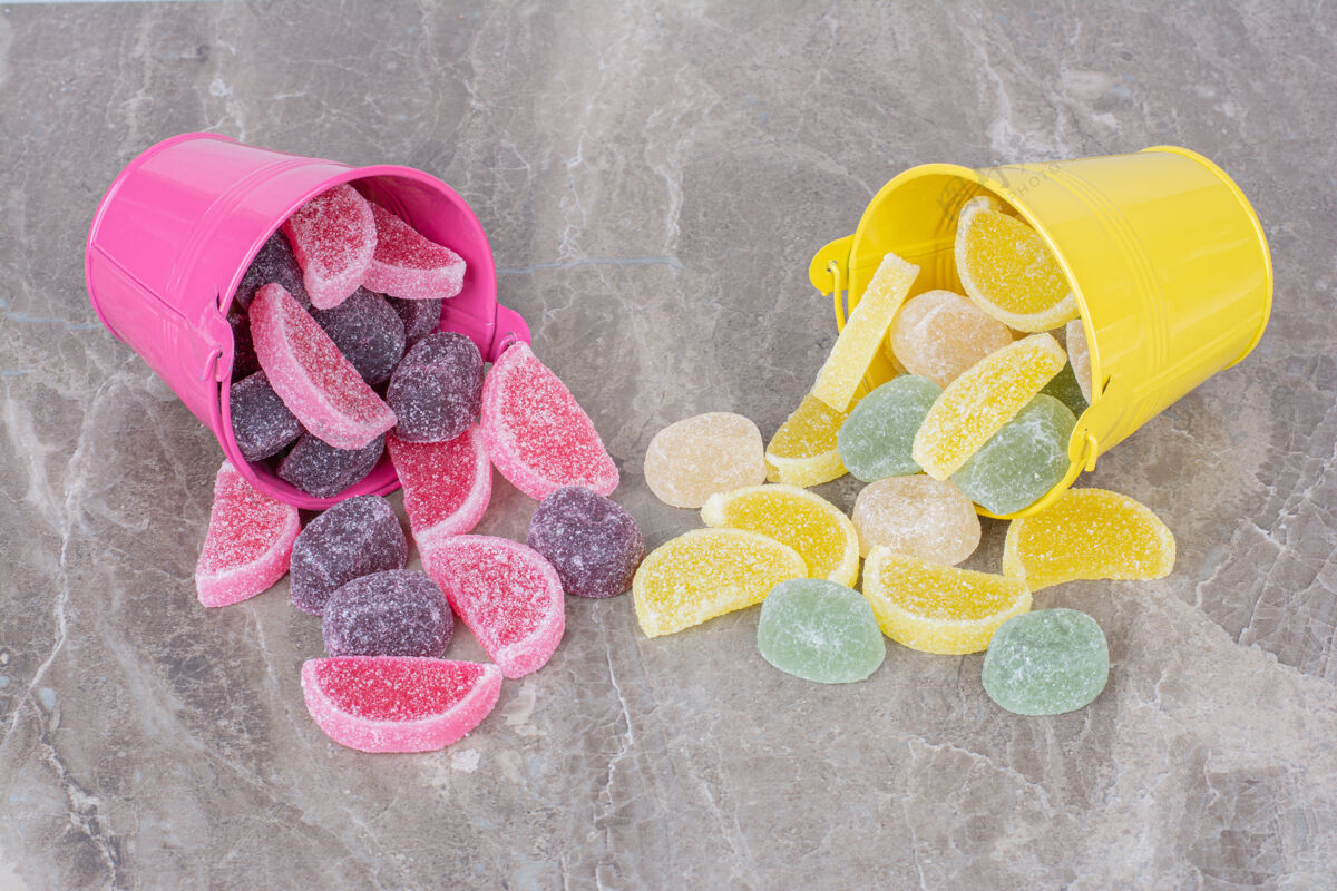 粉色黄色和粉色的桶 大理石背景上有糖果酱桶糖果可口