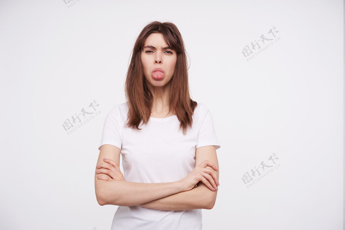 休闲年轻漂亮的黑发女性 穿着休闲服站在白墙上 露出舌头 双手合十放在胸前模特折叠欧洲