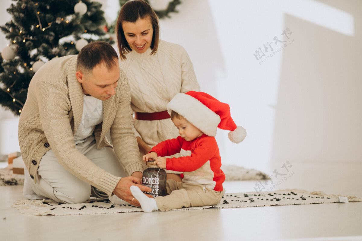 室内一家人带着小儿子在家里的圣诞树旁可爱小男孩男婴