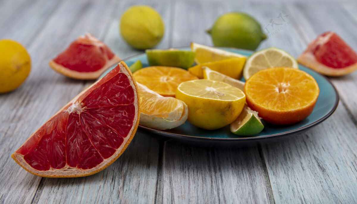 柠檬色前视图葡萄柚楔与柠檬酸橙和橙色楔板上的灰色背景橙色灰色楔形