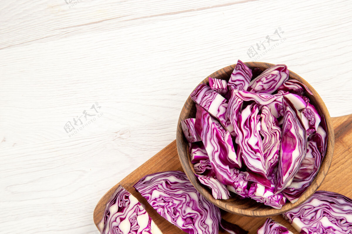 玫瑰上半部分查看切碎的红卷心菜在木碗在切菜板上的白色表面与自由空间视图切卷心菜