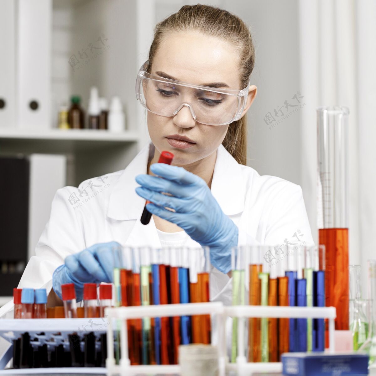 护目镜戴着手套和试管的女研究人员在实验室的正视图专家技术员先驱